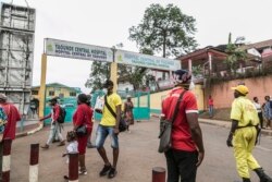 FILE - Some people wear masks as they walk by the entrance to the Yaounde General Hospital in Yaounde on March 6, 2020. Cameroon has been hit harder by the coronavirus than any other country in Central Africa.