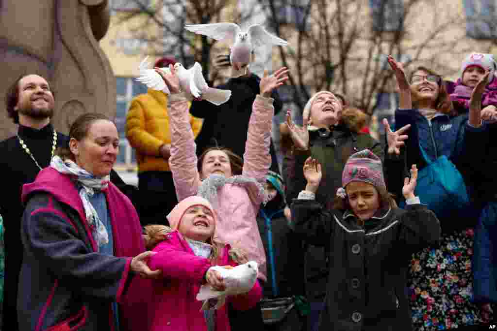 Children and their parents release birds celebrating the Annunciation on the eve of Orthodox Easter in front of the St. Tatiana Church in Moscow, Russia.