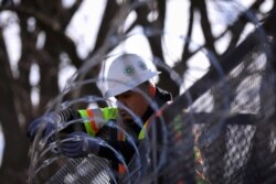 A worker installs razor wire on fencing in front of the U.S. Capitol as an extra security measure in Washington, Jan. 18, 2021.