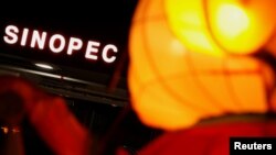 FILE - A Sinopec sign displayed at its gas station is seen behind a Chinese New Year lantern installation in Hong Kong, Feb. 5, 2013.