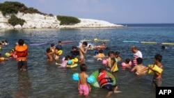 Des enfants réfugiés et migrants apprennent à nager sur la mer près du camp de réfugiés de Kara Tepe à Mytilène, sur l'île de Lesbos, le 10 août 2016.