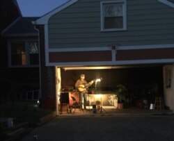 Bill Crandall plays guitar in his garage and shares his performance with neighbors and on social media, in Takoma Park, Maryland. (Mariama Diallo/VOA)