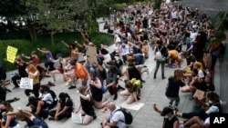 People hold up their first while taking a knee during a protest at the Martin Luther King, Jr., Memorial in Washington, June 19, 2020, while marking Juneteenth.