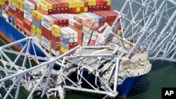 In this aerial image released by the Maryland National Guard, the cargo ship Dali is stuck under part of the structure of the Francis Scott Key Bridge after the ship hit the bridge, Tuesday, March 26, 2024, in Baltimore. (Maryland National Guard via AP)