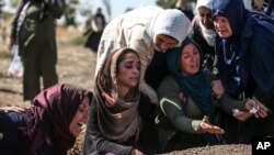 Relatives of Halil Yagmur, 64, who was killed Friday during mortar shelling from Syria, mourn over his grave at the cemetery in the town of Suruc, southeastern Turkey, at the border with Syria, Oct. 12, 2019. 