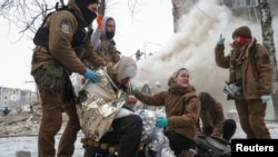 Medical workers treat a wounded local resident at a site of residential buildings heavily damaged during a Russian missile attack, amid Russia's attack on Ukraine, in Kharkiv, Ukraine Jan. 23, 2024.