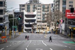 FILE - People cross nearly empty streets in the central business district of Auckland, New Zealand, Aug. 27, 2021.