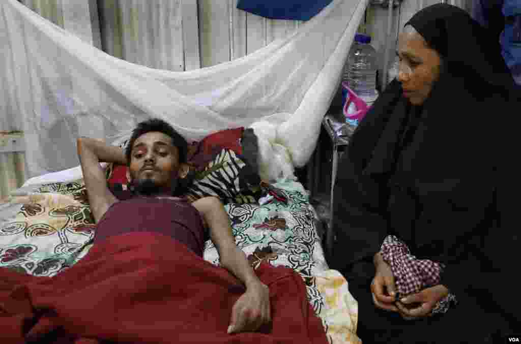 Zohora Hatu (R) stays by her son, Abdur Rahim, 22, in the Primary Care Center of Kutupalong refugee camp April 2, 2019. Rahim is paralyzed from the waist down after a stabbing incident in the camp. (Hai Do/VOA)