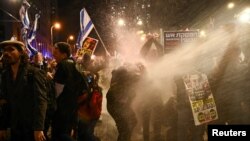 Manifestantes reaccionan cuando la policía usa cañones de agua para dispersarlos durante una protesta contra el gobierno del primer ministro israelí, Benjamin Netanyahu, en medio del conflicto en curso entre Israel y Hamás, en Tel Aviv, Israel, el 24 de febrero de 2024.