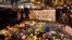 People hold a banner reading "I am Brussels" behind flowers and candles to mourn for the victims at Place de la Bourse in the center of Brussels, March 22, 2016.