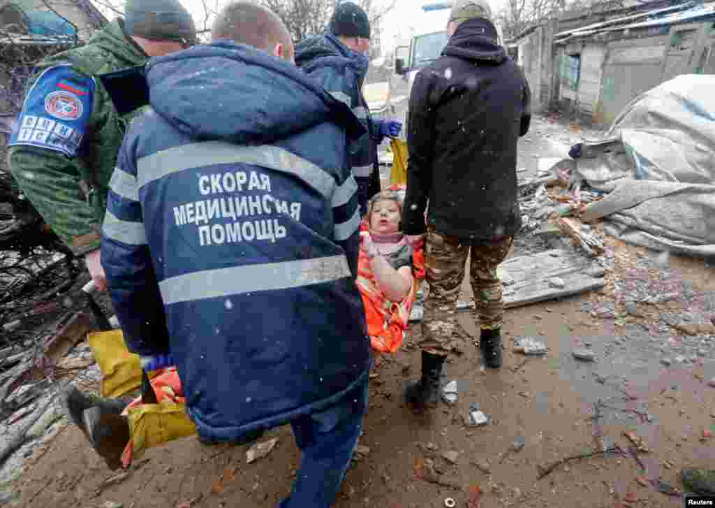 An injured woman is carried out of a damaged house following recent shelling in the separatist-controlled city of Donetsk, Ukraine, March 3, 2022.