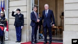 New French prime minister Michel Barnier, right, shakes hands with outgoing prime minister Gabriel Attal during the handover ceremony, Sept. 5, 2024 in Paris. 