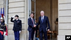 Perdana Menteri Prancis yang baru, Michel Barnier (kana) berjabat tangan dengan pendahulunya Gabriel Attal dalam acara serah terima di Paris pada 5 September 2024. (Foto: Stephane de Sakutin, Pool Photo via AP)