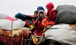 FILE - Internally displaced Syrians from western Aleppo countryside, ride on a vehicle with belongings in Hazano near Idlib, Syria, Feb. 11, 2020.