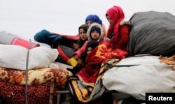 Internally displaced Syrians from western Aleppo countryside, ride on a vehicle with belongings in Hazano near Idlib, Syria, Feb. 11, 2020.