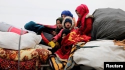 FILE - Syrians from western Aleppo countryside ride with belongings in Hazano near Idlib, Syria, Feb. 11, 2020.