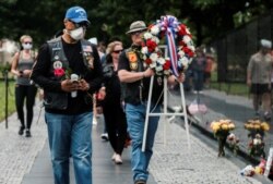 FILE - U.S. veterans, some wearing protective face masks in the midst of the coronavirus disease (COVID-19) pandemic, carry a wreath to the Vietnam Veterans Memorial in Washington.