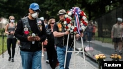 FILE - U.S. veterans, some wearing protective face masks in the midst of the coronavirus disease (COVID-19) pandemic, carry a wreath to the Vietnam Veterans Memorial in Washington.