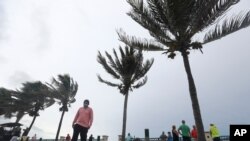 Personas observan las fuertes olas en la playa en Vero Beacch, Florida, el domingo 2 de agosto de 2020.