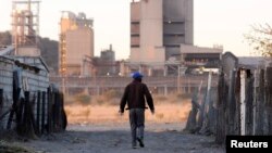 A township resident walks past Lonmin's platinum mine in Marikana, South Africa, June 13, 2014. 