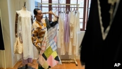 Zhang Na, whose fashion label, Reclothing Bank, sells clothes, bags and other accessories made from materials such as plastic bottles, fishing nets and flour sacks, look at some of the products during an interview at her store in Shanghai on March 19, 2024.