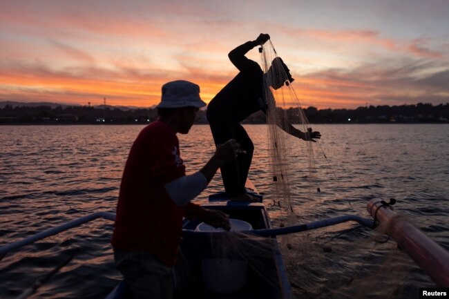 Jessie Cabagbag, 40, who used to be a poacher and is now a sea turtle patroller, hauls his fishing net with another fisherman on his boat in Bacnotan, La Union, Philippines, January 11, 2023. (REUTERS/Eloisa Lopez)