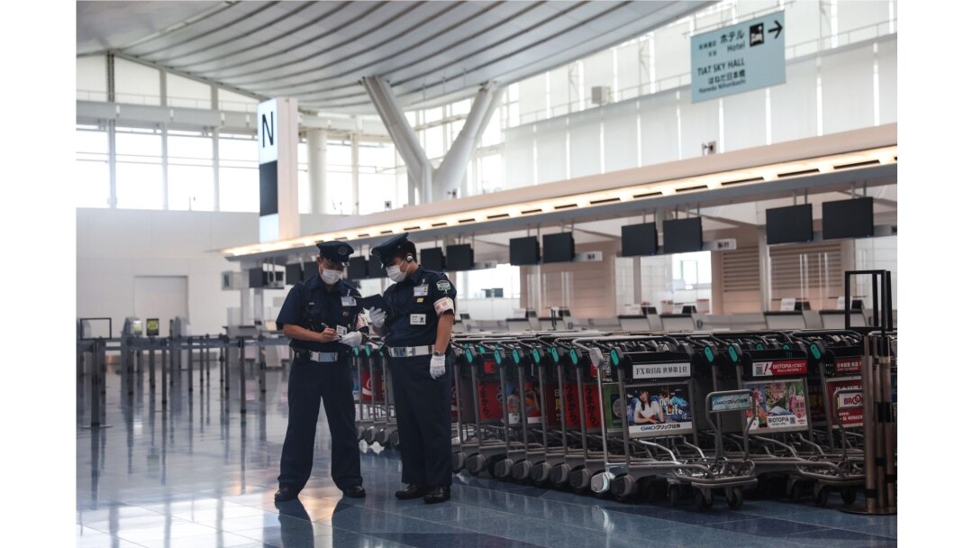 Dos miembros de la seguridad aparecen en la sala de salidas del aeropuerto de Haneda en Tokio el 2 de agosto de 2021, después de que la atleta olímpica bielorrusa Krystsina Tsimanouskaya afirmó que su equipo la estaba obligando a regresar a casa.