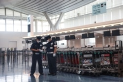 Dos miembros de la seguridad aparecen en la sala de salidas del aeropuerto de Haneda en Tokio el 2 de agosto de 2021, después de que la atleta olímpica bielorrusa Krystsina Tsimanouskaya afirmó que su equipo la estaba obligando a regresar a casa.