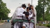 Indian schoolchildren use a plastic sheet to keep dry as they ride a cycle-rickshaw during a light drizzle in New Delhi. 