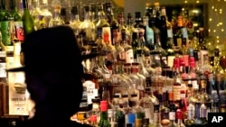 FILE - Bottles of alcohol sit on shelves at a bar in Houston, June 23, 2020. 