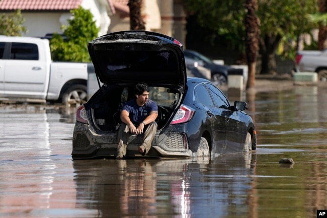 FILE - Dorian Padilla sits in his car as he waits for a tow after it got stuck in the mud on a street after Tropical Storm Hilary swept through the area Monday, Aug. 21, 2023, in Cathedral City, Calif. (AP Photo/Mark J. Terrill)