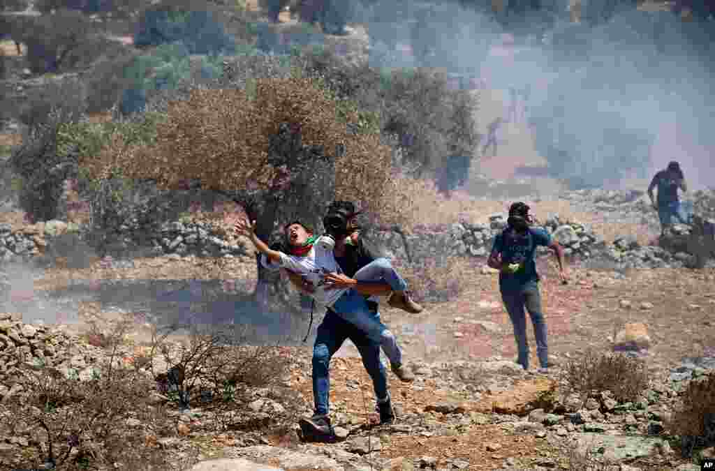 Palestinians carry a boy away from the gas tear canisters fired by Israeli soldiers during a protest against the West Bank Jewish settlement outpost of Eviatar that was rapidly established last month, near the West Bank city of Nablus.