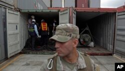 FILE - A police officer stands guard as investigation officers look inside a container holding military equipment aboard the North Korean-flagged freighter Chong Chon Gang at the international container terminal at Colon City, Panama.