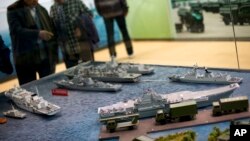 FILE - Visitors look at a scale model of Chinese aircraft carrier Liaoning (bottom right) among the naval ships on display at an exhibition held ahead of the 18th National Congress of the Communist Party of China in Beijing, Nov. 5, 2012.
