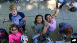 Ova fotografija javne škole Spokane prikazuje učenike petog razreda osnovne škole Adams kako zastaju da poziraju za fotografiju dok slikaju mural na Spokane Community Collegeu, maja 2024., u Spokaneu, Washington. (Spokane Public Schools preko AP-a)