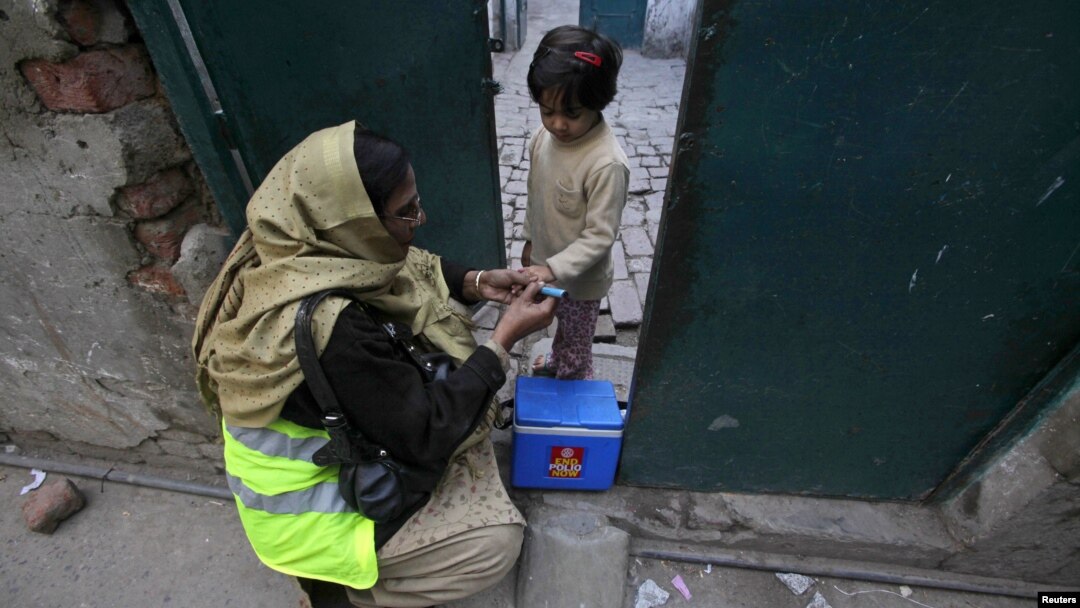 Petugas polio bernama Nishat memberikan vaksin polio pada seorang anak perempuan di Lahore, Pakistan (20/12). (Foto: Reuters)