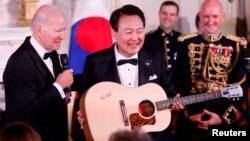 U.S. President Joe Biden presents a guitar signed by artist Don McLean to South Korea's President Yoon Suk Yeol at an official State Dinner, during South Korea's President Yoon Suk Yeol's visit, at the White House in Washington, April 26, 2023.