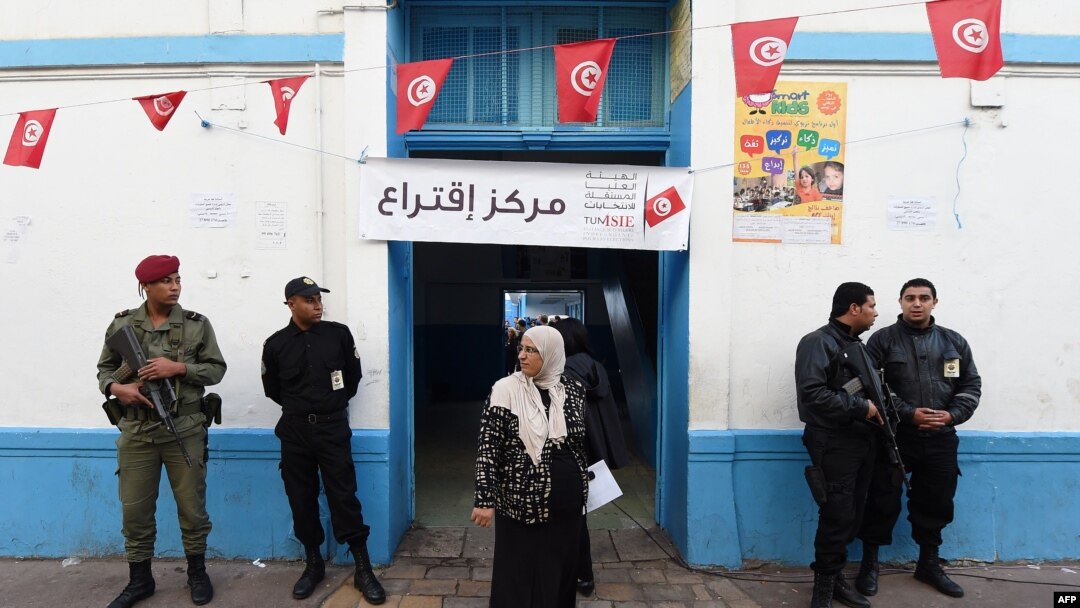 Petugas keamanan Tunisia berjaga-jaga di luar TPS di pusat kota Tunis pada 23 November 2014, dalam pemilihan presiden Tunisia pertama sejak revolusi tahun 2011. 