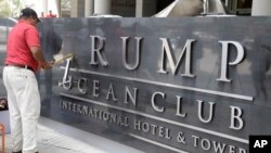 FILE - A man removes the word Trump off a marquee outside the Trump Ocean Club International Hotel and Tower in Panama City, March 5, 2018. 