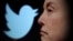 FILE - Twitter logo and a photo of Elon Musk are displayed through magnifier in this illustration taken October 27, 2022. 