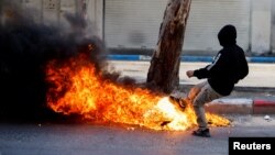 A Palestinian kicks a burning object during clashes between Palestinians and Israeli soldiers following the death of Palestinian prisoner Khader Adnan during a hunger strike in an Israeli jail, in Hebron in the Israeli-occupied West Bank May 2, 2023.