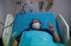 Geetika, 45, who is suffering from coronavirus disease, gestures as she receives treatment inside the emergency room of Safdarjung Hospital in New Delhi, India, May 7, 2021.