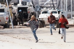 FILE - Civilians run along Sarajevo’s notorious “Sniper Alley,” as French U.N. peacekeepers look on, April 5, 1995.