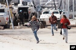 FILE - Civilians run along Sarajevo’s notorious “Sniper Alley,” as French U.N. peacekeepers look on, April 5, 1995.