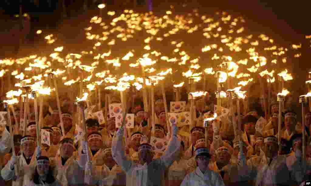 Warga Korea Selatan menggunakan baju tradisional dengan membawa obor dan bendera nasional berbaris di jalanan wilayah Cheonan, selatan Seoul dalam upacara Peringatan Gerakan Kemerdekaan 1 Maret, untuk merayakan ulang tahun pergerakan melawan penjajahan Jepang tahun 1919.