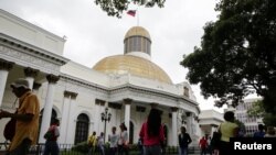 Personas pasan frente al edificio de la Asamblea Nacional durante una sesión parlamentaria en Caracas, el 14 de diciembre de 2016. 