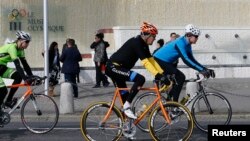 U.S. Secretary of State John Kerry (C) cycles past the Olympic Museum in Lausanne, France, March 16, 2015. 