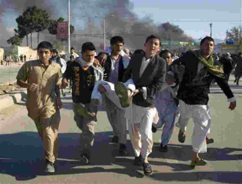 Afghans carrying a man, who got wounded following an attack on UN's office during a demonstration to condemn the burning of a copy of the Muslim holy book by a Florida pastor, in Mazar-i- Sharif north of Kabul, Afghanistan on Friday, April. 1, 2011. An Af