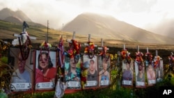 FILE - Photos of victims are displayed under white crosses at a memorial for the August 2023 wildfire victims, above the Lahaina Bypass highway, Dec. 6, 2023, in Lahaina, Hawaii. 
