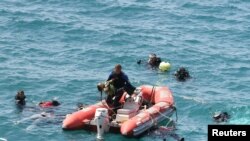A diver from the Turkish sea police (C) carries a girl in a rescue boat as other divers look for victims in the Aegean sea off Menderes, western Turkey, September 6, 2012.